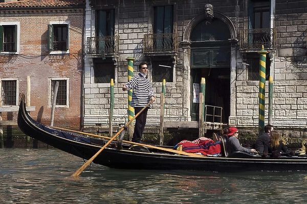 Europe, Italy, Venice. A gondolier strikes a pose on his gondola