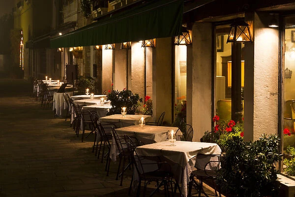 Europe, Italy, Venice. Restaurant tables lit at night