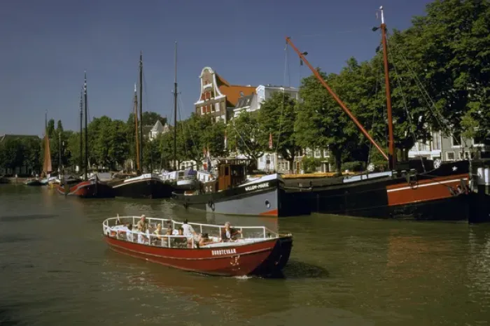 Framed Print : Europe, Netherlands, Dordrecht. Boats lining canal, with tourist boat motoring by
