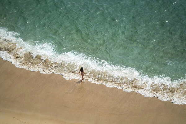 Europe, Portugal, Nazare. Girl in surf on beach