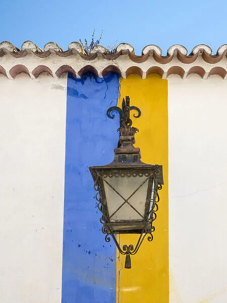 Europe, Portugal, Obidos. Wrought iron lantern hanging from a colorful stripped wall
