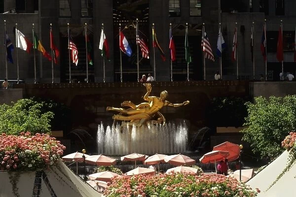Famous RCA gold statue in Rockefeller Center with flags and flowers and cafe in New York City USA