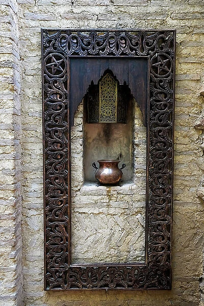 Fes, Morocco. Old copper pot sits on a ledge with a carved wooden frame
