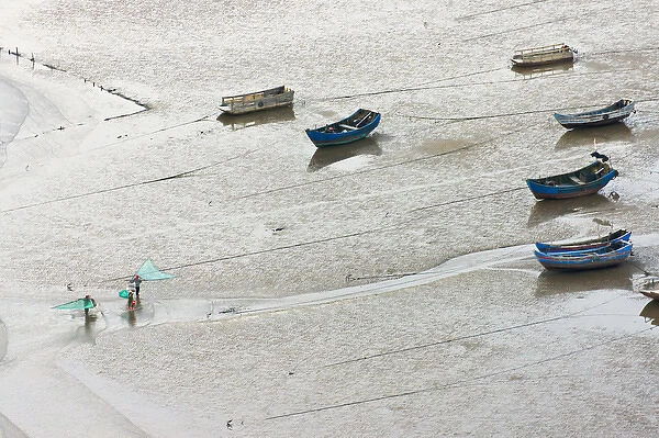 Fishermen carrying fish net and fishing boats on the muddy beach, East China Sea