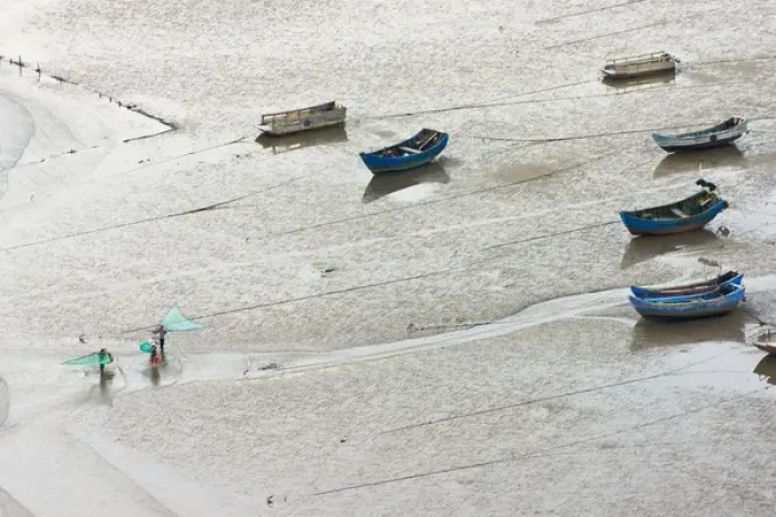 Framed Print : Fishermen carrying fish net and fishing boats on the muddy beach, East China Sea