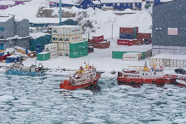 Fishing boats in the frozen harbor during a snow storm. Ilulissat, Greenland. (Editorial Use Only)