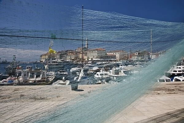 Fishing nets and harbor in front of distant Cathedral of St. Euphemia, Rovigno, Croatia