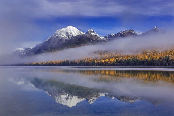 Fog lifts from Rainbow Peak and Bowman Lake in autumn in Glacier National Park, Montana