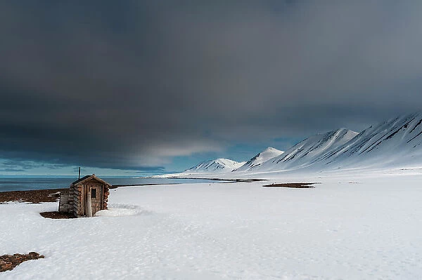 A fox hunting log cabin on the snow covered beach at Mushamna, Spitsbergen Island, Svalbard, Norway