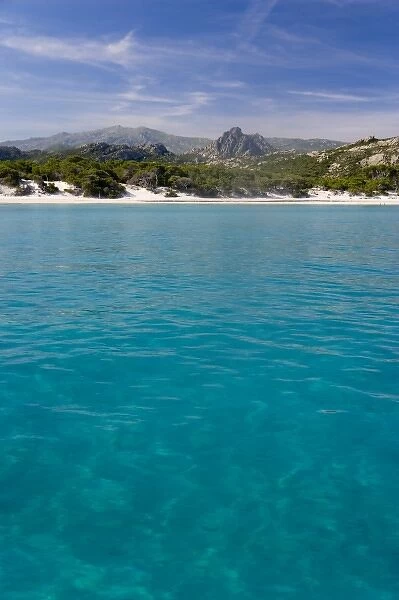 France, Corsica. Clear water and white sand at Saleccio Beach below rugged terrain of DA