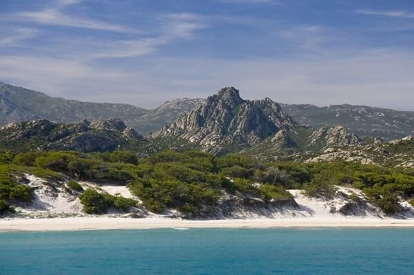 France, Corsica. White sand and clear water at Saleccio Beach below rugged terrain