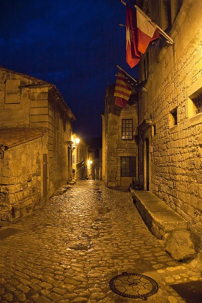 France, Provence, Les Baux-de-Provence. Flags over deserted street inside castle at night