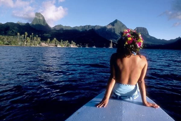 French Polynesia, Moorea. Woman enjoying view on bow of boat wearing flower garland