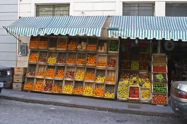 A fruit and vegetable shop displaying products in wooden crates on the street: tomatoes