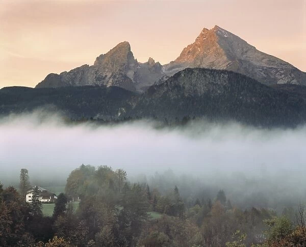 Germany, Bavaria, Berchtesgaden. A farmhouse sits in the fog at the base of the Watzmann Mountains