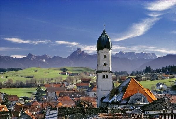 Germany, Bavaria, Nesselwang. The spire of a village church stands out from the mountains peaks