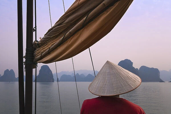 Girl with conical hat on a junk boat and karst islands in Halong Bay, UNESCO World