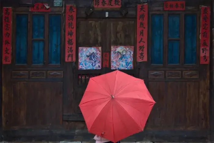 Framed Print : Girl with red umbrella watching traditional wood door decorated by poster of guarding god