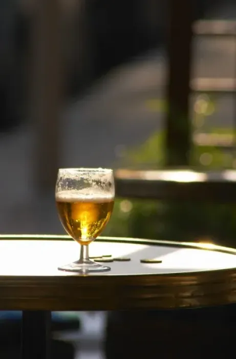 Framed Print : A glass of beer with foam froth with sun backligthing the drink and some change coins