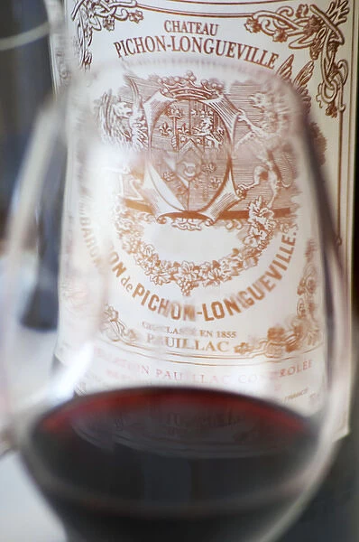 A glass of wine with the label of a bottle seen through the glass - label without vintage