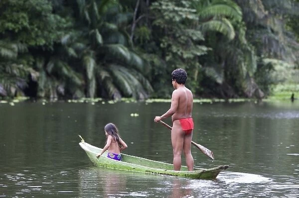 Goa Panama. A Wounaan father and daughter canoing down the charges river in the rain