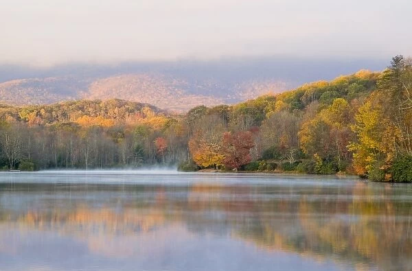 Grandfather Mountain lights up at sunrise as Price Lake reflects fall colors near