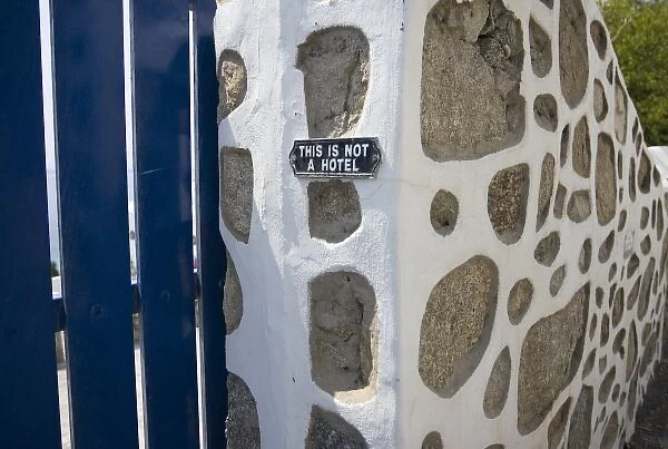 Greece, Mykonos. Gate and stone wall with caution notice for tourists, This is not a hotel