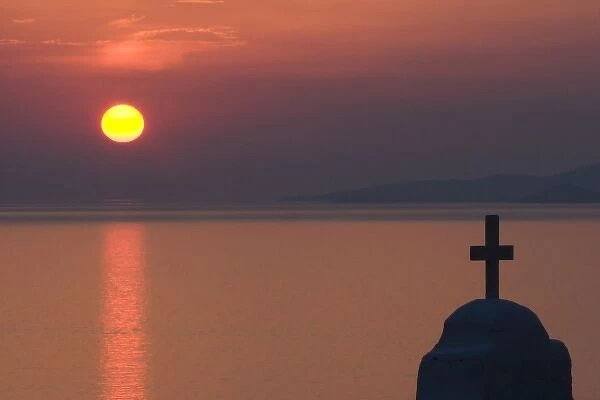 Greece, Mykonos, Hora. Sunset silhouettes Greek Orthodox church and cross in foreground