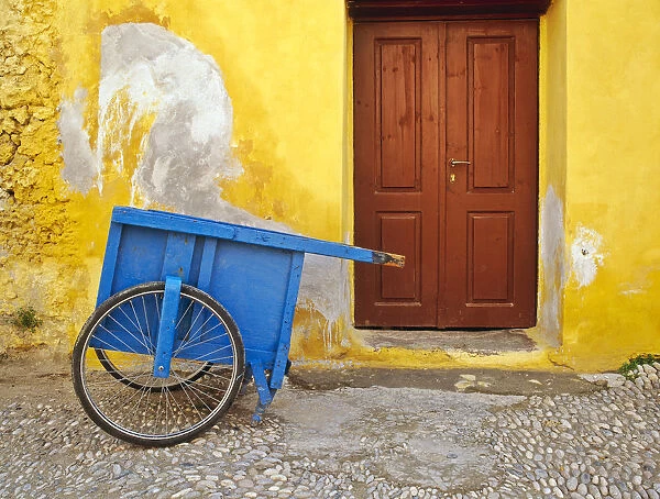 Greece, Rhodes. House with blue cart in front