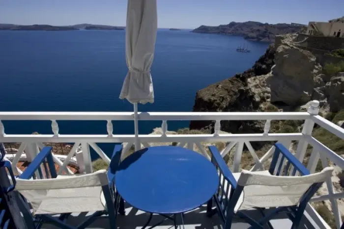 Framed Print : Greece, Santorini. Blue and white patio chairs and table overlooking Aegean Sea