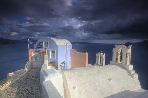 Greece, Santorini, Evening light in Oia town with bell towers and colorful building on point