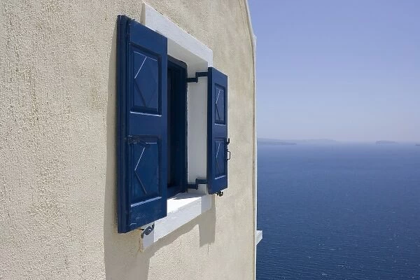 Greece, Santorini, Thira, Oia. Blue-shuttered window in pale yellow wall overlooking blue sea