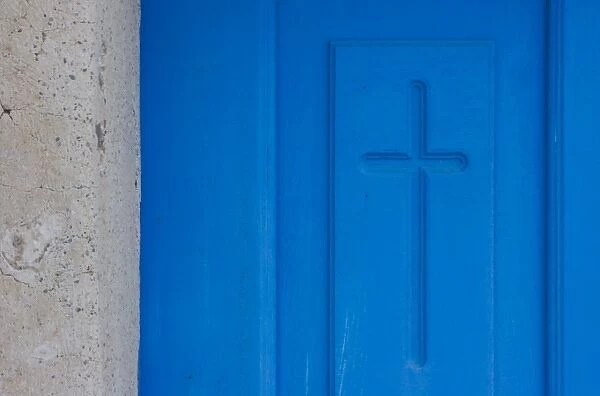 Greece, Santorini, Thira, Oia. Christian cross symbol engraved in blue door