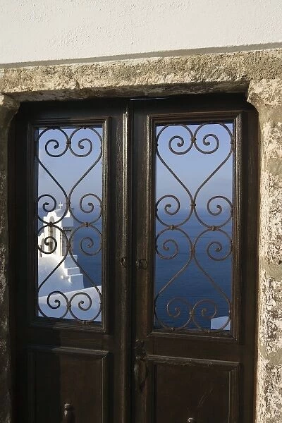 Greece, Santorini, Thira, Oia. Church tower seen through iron grill of door with sea in background