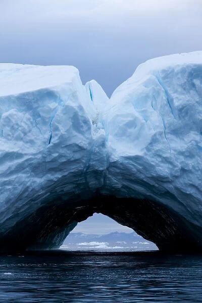 Greenland, Ilulissat, Arch formed within melting iceberg grounded near face of Jakobshavn