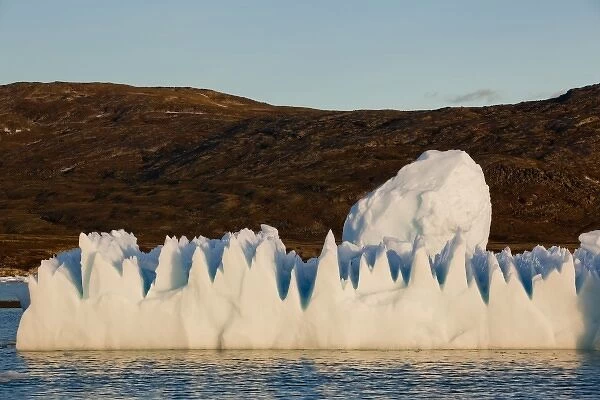Greenland, Ilulissat, Setting midnight sun lights jagged floating iceberg near Eqip