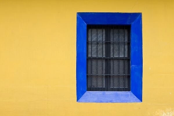 Guatemala, Antigua. Blue window against bright yellow wall