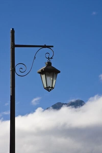 Guatemala, Antigua. Lamp post with Volcano Agua in background covered with clouds