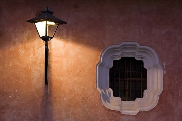 Guatemala, Antigua. Lantern on a colorful wall turned on in the evening