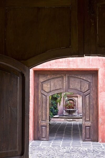 Guatemala, Antigua. Looking through two doorways at a hotel fountain decorated with flowers