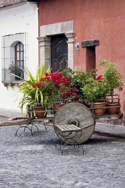Guatemala, Antigua. An old wooden cart filled with flowers on the streets of Antigua