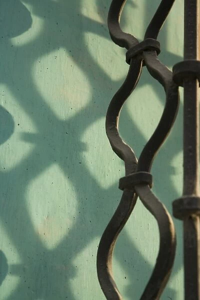 Guatemala, Antigua. Wrought-iron window grate, with shadows on turquoise wall