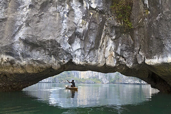 Ha Long Bay, Vietnam. View of kayaker through limestone arch
