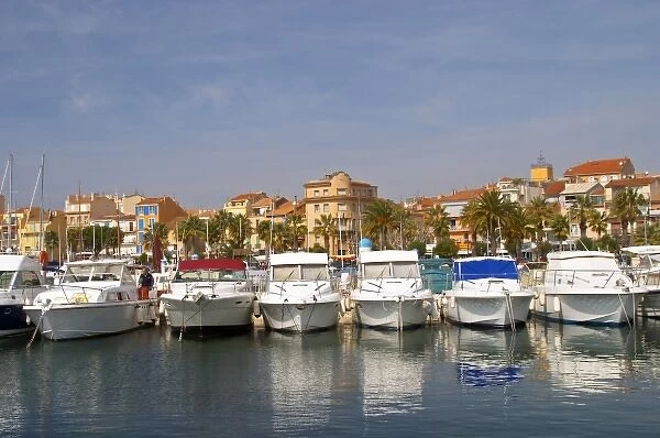 The harbour with boats and buildings along the water in Bandol. White motor yachts