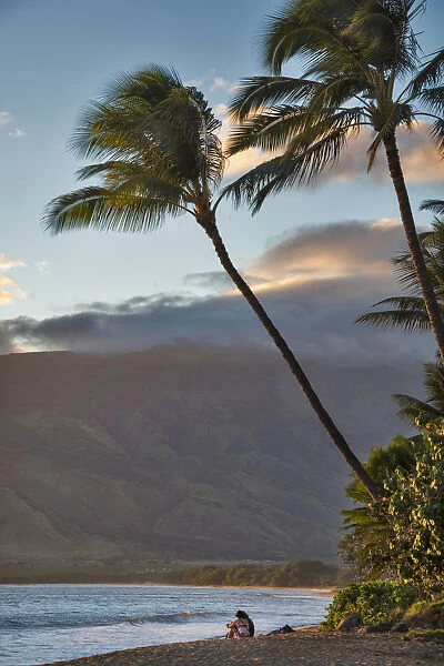 Hawaii, Maui, Kihei. Tourists walking under palm trees on Ka Lae Pohaku beach