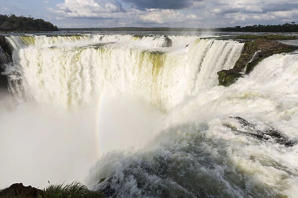 The headwater of Iguazu Falls with a rainbow from the Argentinian side with Brazil in the background