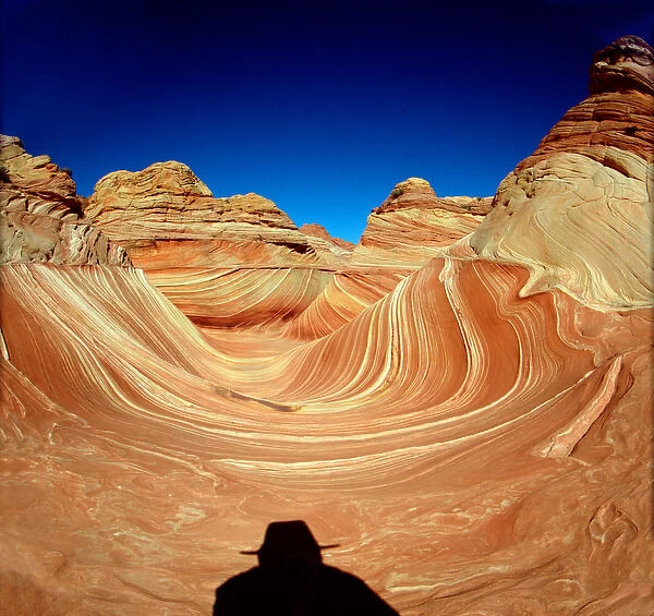 Hiker in the Wind and water eroded Navajo sandstone in Coyote Buttes North, Paria