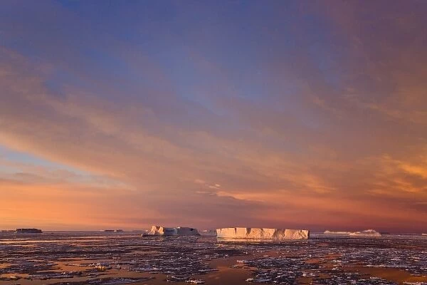 Huge iceberg and ice floes in the ocean at sunrise, Antarctica