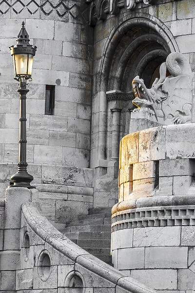 Hungary, Budapest. Light hitting lamppost, staircase, and dragon statue on Fisherman