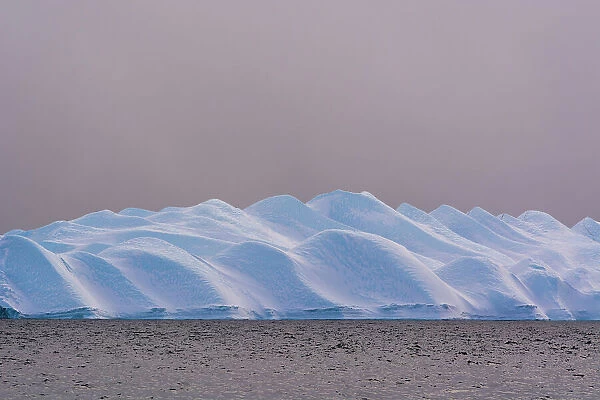 An iceberg in Ilulissat Icefjord, a UNESCO World Heritage Site, on a cloudy day. Ilulissat Icefjord, Ilulissat, Greenland